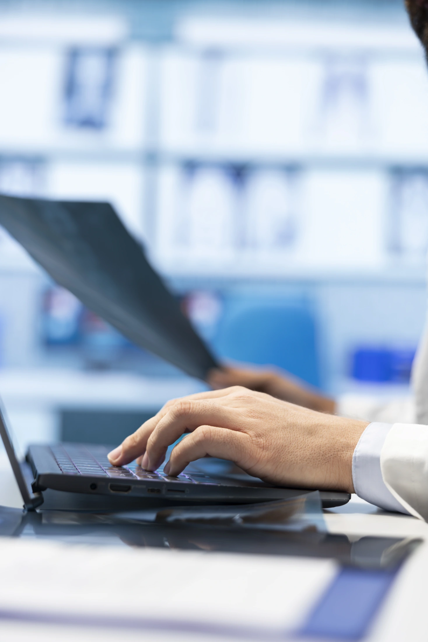 Close-up of hands working on a laptop at a desk